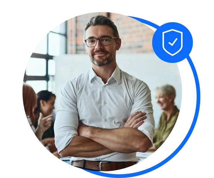 Male wearing a white buttoned up start standing cross armed in an office meeting room